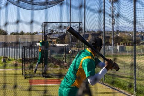 Cricket batter practicing in net cage during outdoor team training session