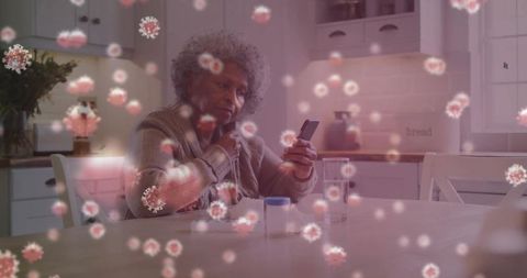 Senior Woman Reflecting with Smartphone in Kitchen as Virus Particles Float Around