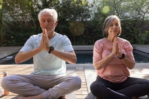 Senior Couple Outdoors Practicing Meditation by Poolside