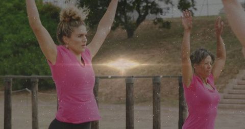 Women Exercising Outdoors with Parallel Bars in Vibrant Pink