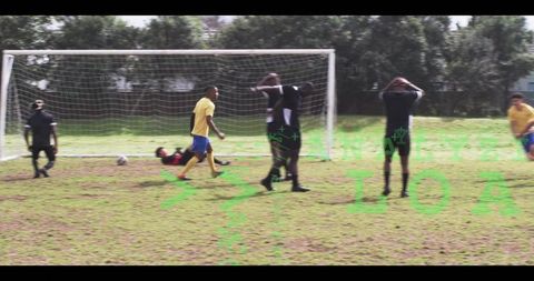 Goalkeeper diving while defenders reacting to close shot on grass soccer pitch