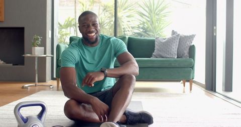 Smiling Man in Workout Clothes Relaxing at Home with Kettlebell