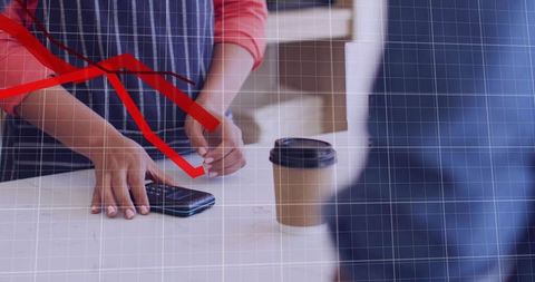 Barista processing mobile payment at cafe counter with takeaway coffee cup and card reader