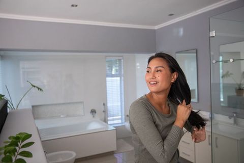 Woman Grooming Hair in Modern Bathroom