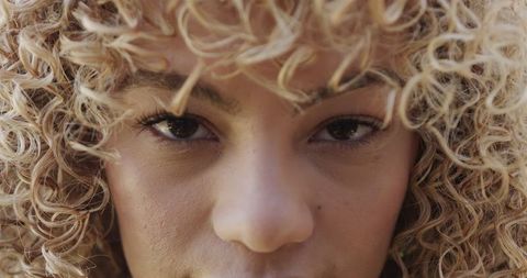 Joyful Young Woman with Curly Hair Smiling Confidently