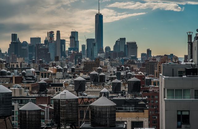 New York City skyline featuring distinctive water towers on building rooftops against a cloudy sky. Ideal for use in tourism campaigns, urban study presentations, city planning projects, architecture blogs, and metropolitan lifestyle promotions.