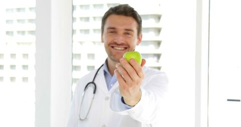 Doctor Promoting Healthy Eating with Green Apple in Hospital