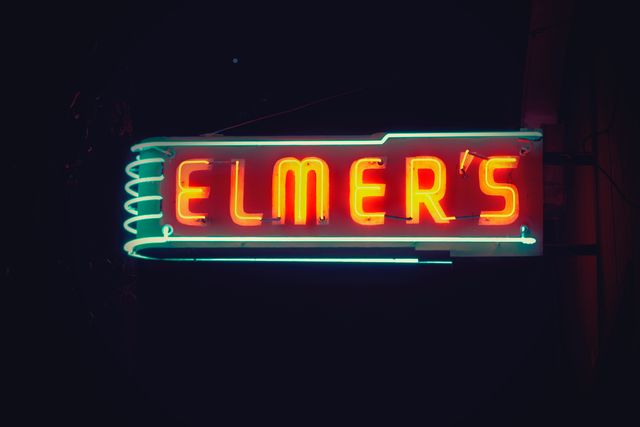 Colorful neon sign for Elmer's diner glowing at night. Retro and vintage vibes perfect for marketing materials related to restaurants, nighttime city scenes, retro-themed projects, and advertisements.