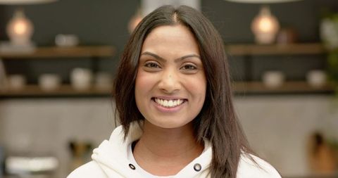 Smiling woman organizing cups in modern kitchen