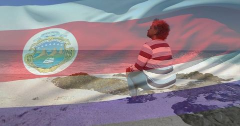 Solitary man sitting on coastal rocks gazing at ocean with costa rica flag overlay, serene