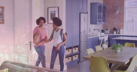 Mother greeting daughter returning home in modern blue open-plan kitchen