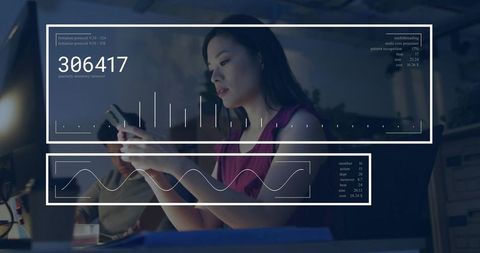 Chinese woman using smartphone with futuristic hud analytics overlay working late at desk