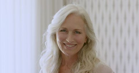 Confident Mature Woman Smiling Indoors with Long White Hair