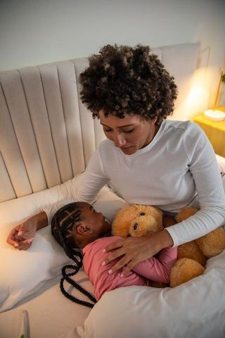 Mother Embracing Daughter in Bed for Tranquil Sleep