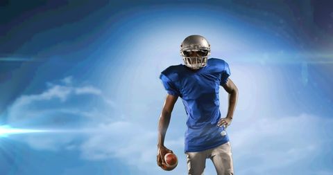 American Football Player Posing Against Dramatic Sky Background
