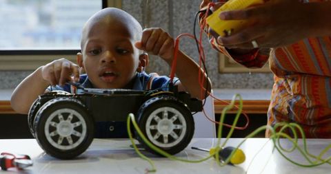 Father and son repairing toy car together at home