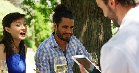 Smiling Friends Ordering at Outdoor Garden Restaurant