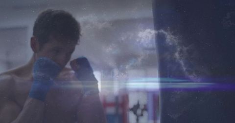 Moody double-exposure boxer training with heavy bag, nebula overlay and blue hand wraps
