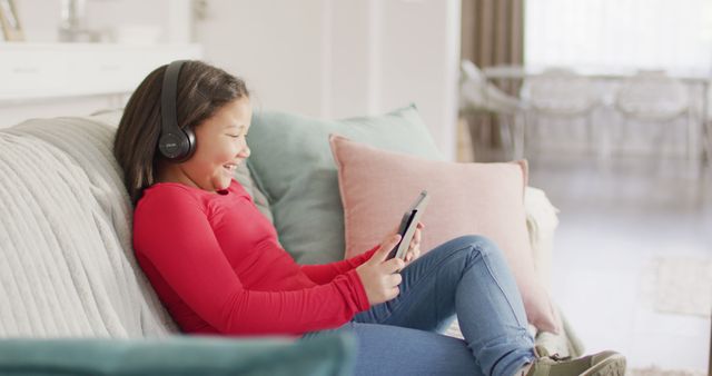 Image of happy asian girl resting on sofa with smartphone. Childhood, relax, spending time at home with technology concept.