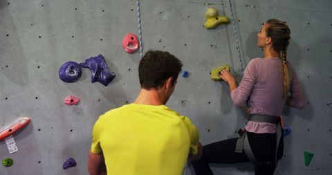 Couple indoor rock climbing with safety gear