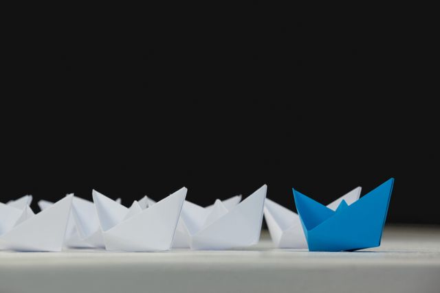 Paper boats arranged together on white surface