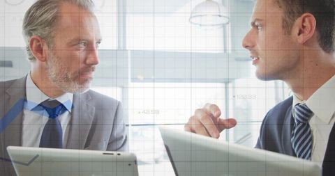 Senior and Junior Executives Discussing Strategy While Using Tablets in Modern Boardroom