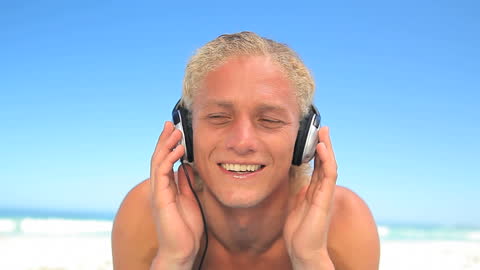 Smiling Man Enjoying Music on Beach with Headphones