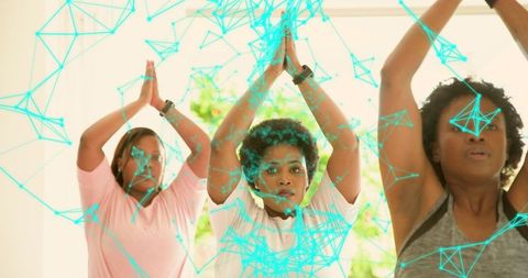 Midlife women practicing yoga together in studio with futuristic digital network overlay