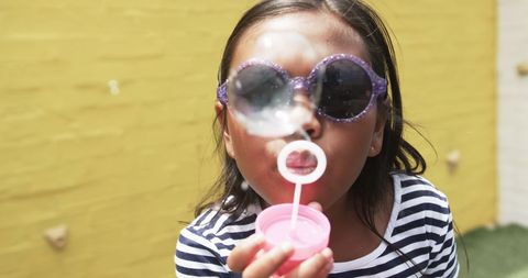 Playful Girl Blowing Bubbles with Sunglasses in Bright Schoolyard - Download Free Stock Images Pikwizard.com