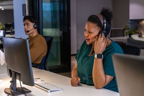 Customer support team speaking on headsets in modern office, african american woman on call
