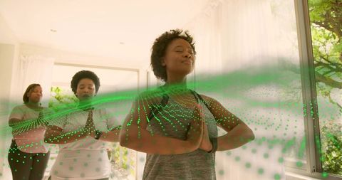 Women practicing mindfulness and yoga with green augmented reality wave in airy studio