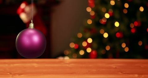 Purple Bauble over Wooden Table with Christmas Tree View - Download Free Stock Images Pikwizard.com