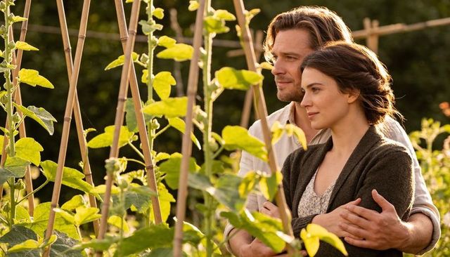 Romantic couple embracing in sunlit garden by bamboo trellis at golden hour