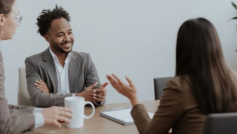 Smiling businessman listening and engaging in team meeting at conference table