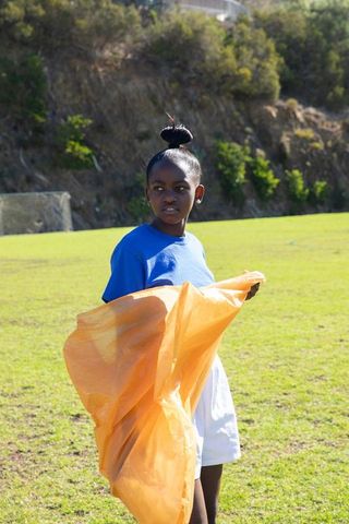 Young Girl Holding Bright Scarf on Athletic Field