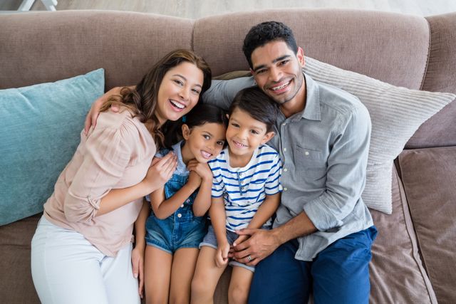 Portrait of happy parents and kids sitting on sofa in living room at home