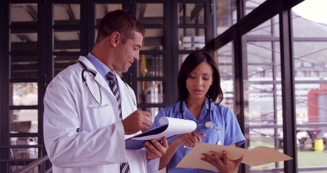 Medical professionals discussing patient records in a hospital. The image shows a doctor and a nurse reviewing charts together, symbolizing teamwork and communication in healthcare. Perfect for use in medical articles, healthcare blogs, and educational materials about hospital procedures and teamwork.