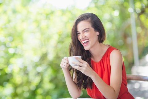 Joyful Woman in Red Laughing at Outdoor Cafe