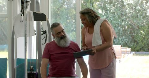 Senior Couple Discussing Fitness Routine with Tablet at Home
