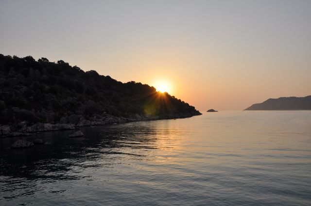 Serene Sunset Over Calm Sea with Rocky Shoreline - Download Free Stock Photos Pikwizard.com
