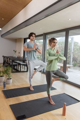 Couple Practicing Yoga Tree Pose in Modern Living Space for Wellness