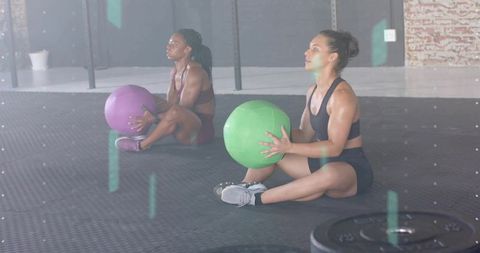 Partners training with medicine balls holding green and purple balls for core strength