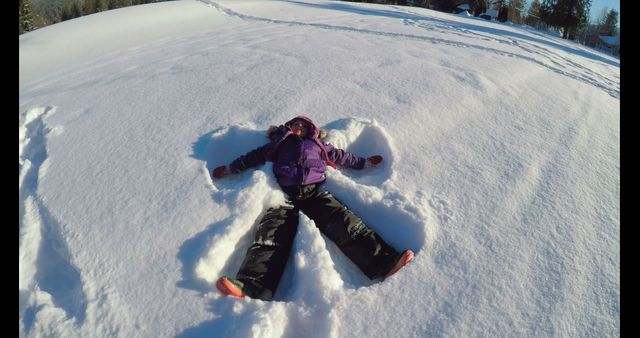 Caucasian boy makes a snow angel in a winter landscape, with copy space. Outdoor fun captured as he enjoys a snowy day.