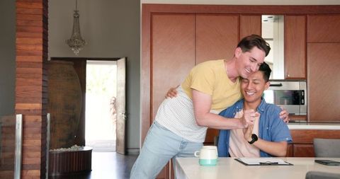 Happy LGBTQ+ Couple Reviewing Documents at Kitchen Counter