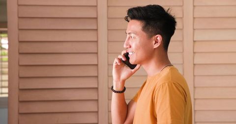 Casual asian man communicating on smartphone indoors