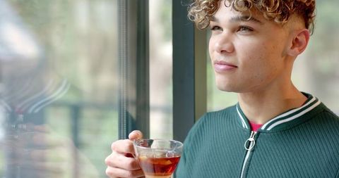 Man enjoying warm beverage by window with view