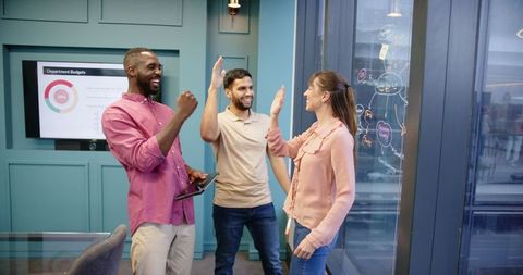Diverse Team Celebrating Success in Modern Office with High Fives