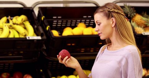 Woman selecting apple in grocery store produce section