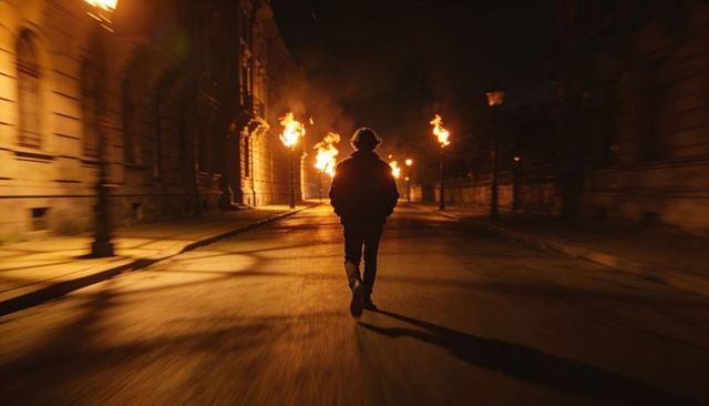 Walking silhouette through torchlit night street casting long shadow, lone urban figure