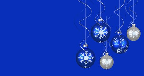 blue christmas ornaments decorated with snowflake designs hang against a solid blue background. these festive balls, combined with swirling strings, offer elegant seasonal decoration options perfect for holiday cards, festive invitations, newsletters or social media banners promoting winter sales and celebrations.